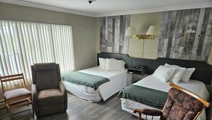 Een hotelkamer met twee bedden, een stoel, een nachtkastje en een lamp.