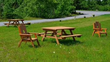 En picknickplats med ett träbord och stolar på en gräsig äng.