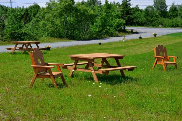 A picnic setup with a wooden table and chairs in a grassy field. - Silverwood Inn (Bay Roberts)