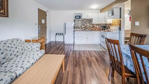 Un espacio habitable compacto con sofá, mesa de comedor y sillas, una kitchenette con microondas y armarios, y piso con diseño.