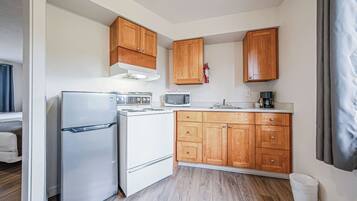 Una cocina compacta con armarios de madera, un refrigerador, un microondas y una estufa.