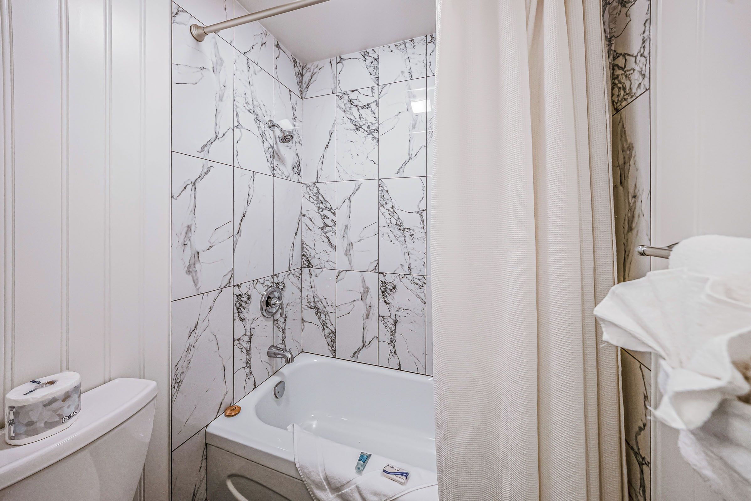 A bathroom with a bathtub, toilet, and shower curtain.