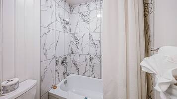 A bathroom with a bathtub, toilet, and shower curtain.