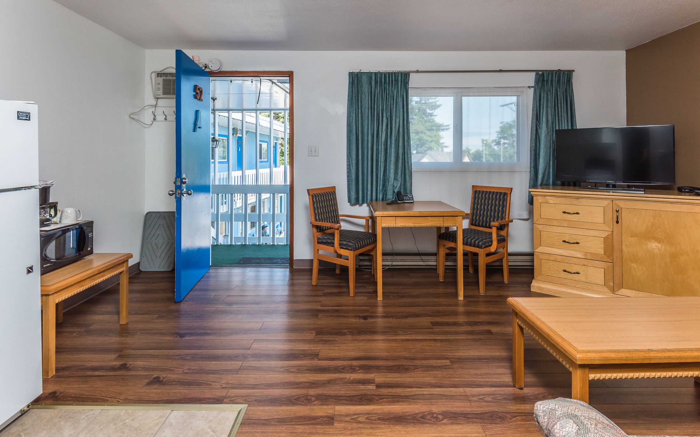 A compact living space with a dining area, a television, and a kitchenette.