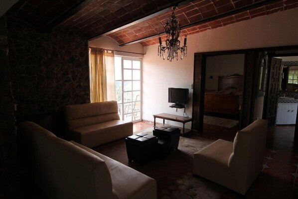 A living room with a sofa, armchairs, a TV, and a chandelier.