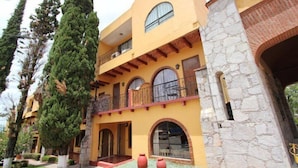 A multi-story building with a yellow facade, stone accents, and balconies. - Hotel Villa de la Plata (Guanajuato)