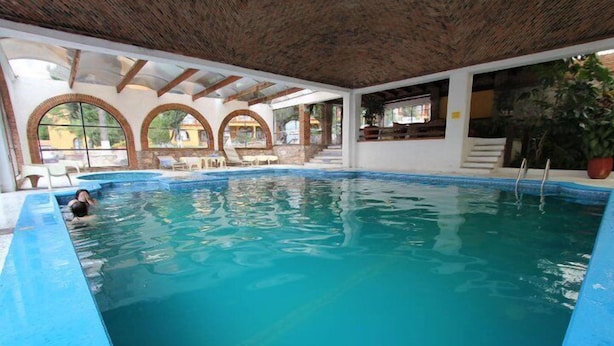 An indoor swimming pool with clear water, a tiled floor, and a wooden ceiling. - Hotel Villa de la Plata (Guanajuato)