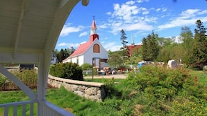 Eine weiße Kirche mit rotem Dach und einem Kirchturm, umgeben von Grünflächen und Bäumen.