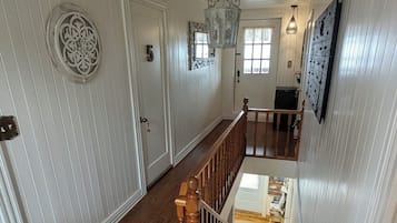 A wooden staircase leading to a second-floor landing with a view of the lower level.