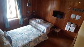 Een houten kamer met twee bedden, een televisie en een kleine tafel.
