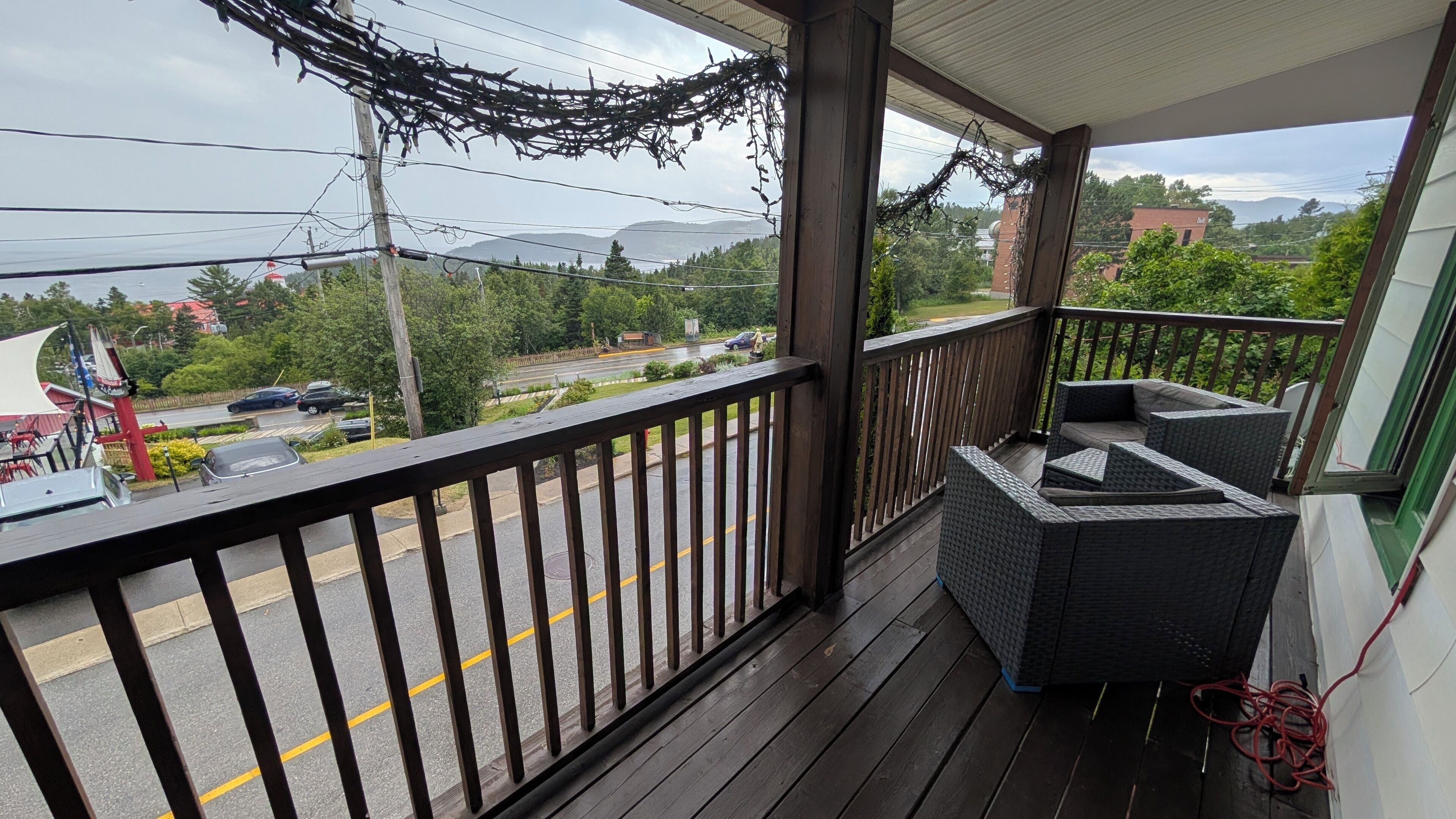 A wooden balcony with a view of a road and greenery.