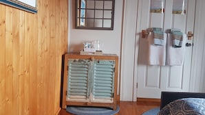 Ein Zimmer mit Holzwänden, einem alten Schrank, einem Spiegel und einer Tür mit Handtüchern und einem Schild.