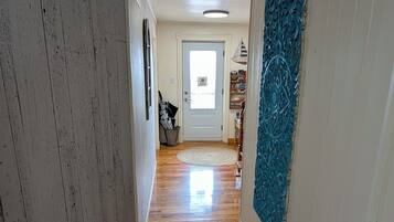 Un pasillo con suelo de madera, paredes blancas y un panel decorativo azul.