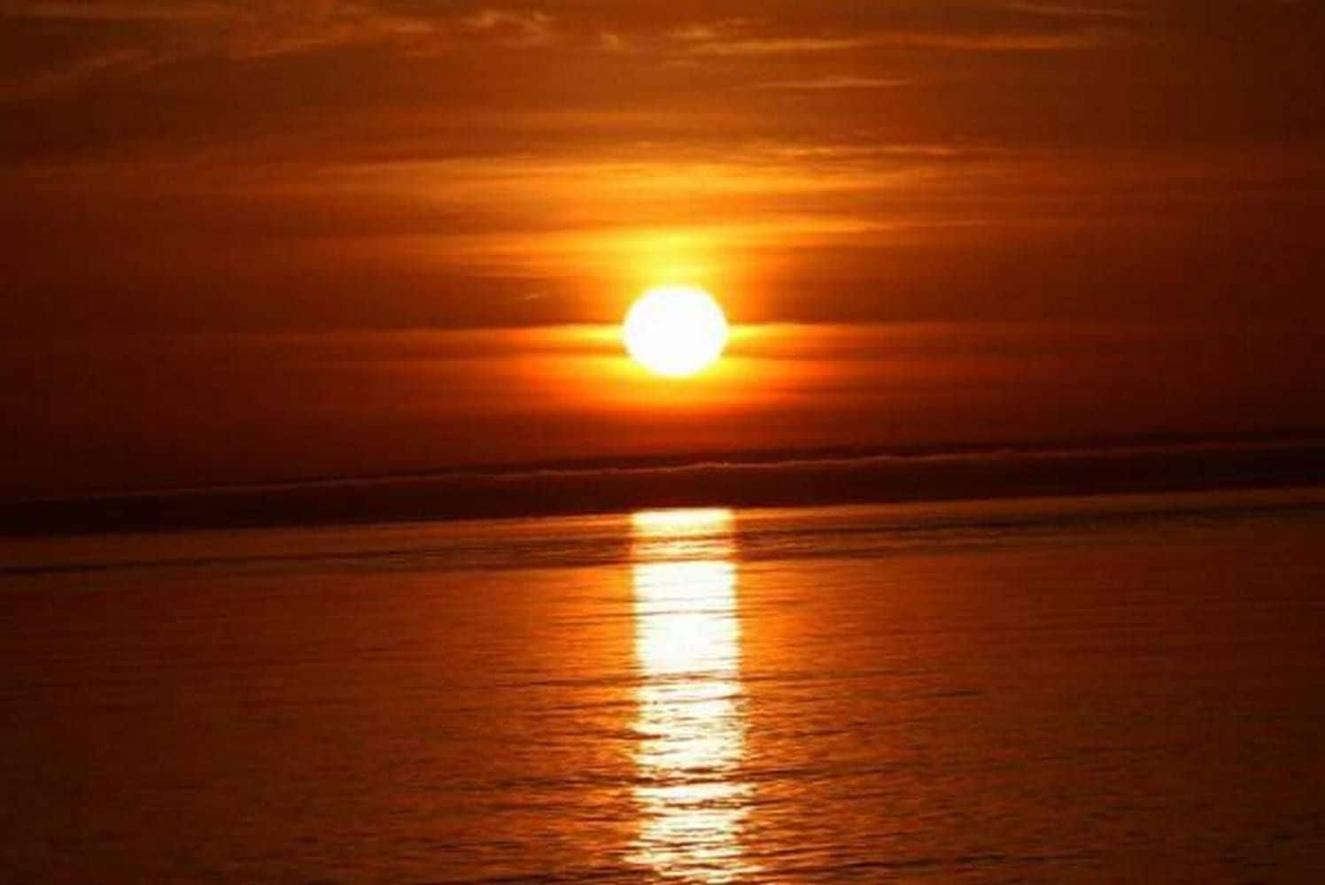 Un coucher de soleil sur une étendue d’eau calme.