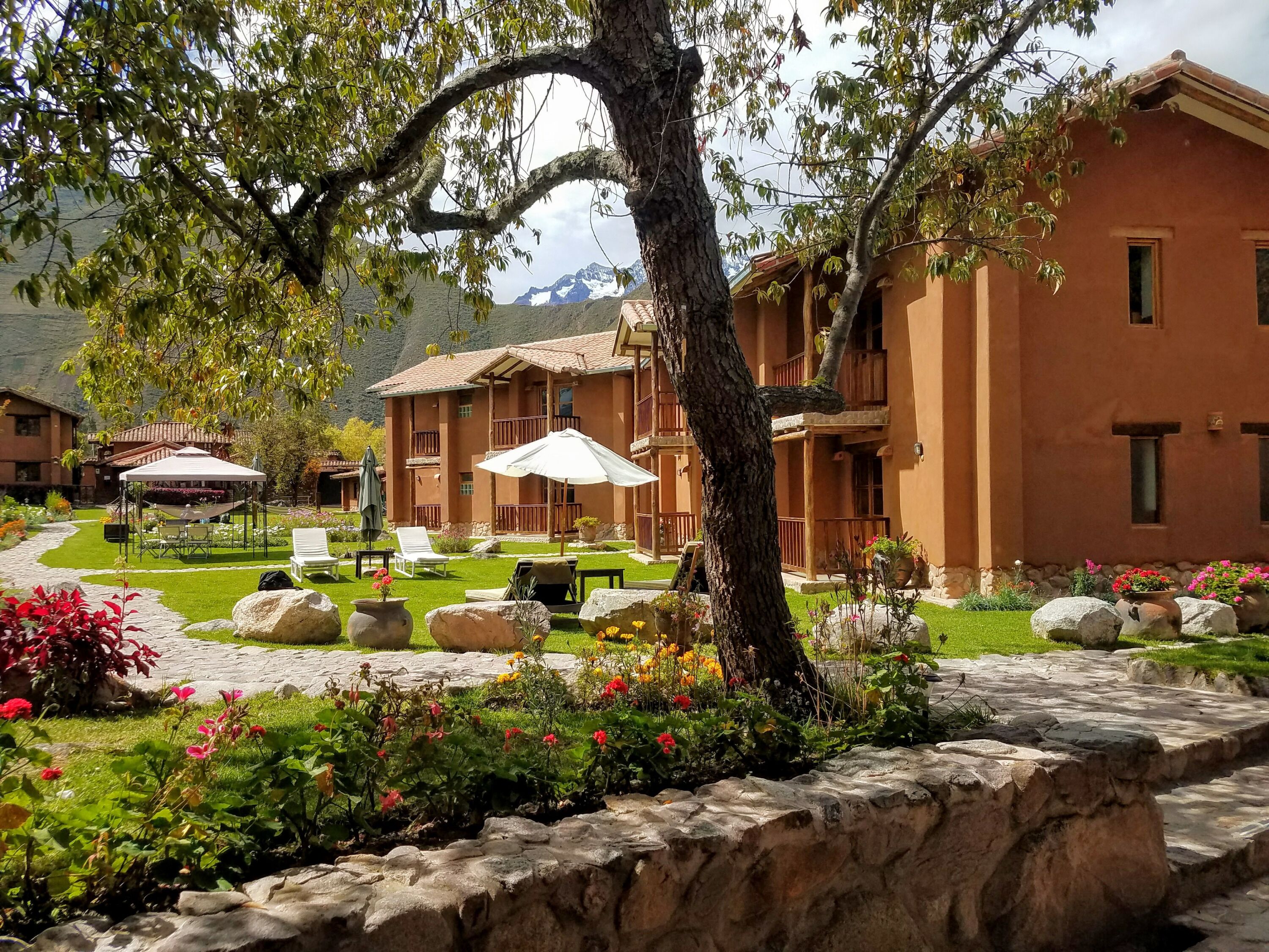 A hotel with outdoor seating, a garden, and a mountain view.