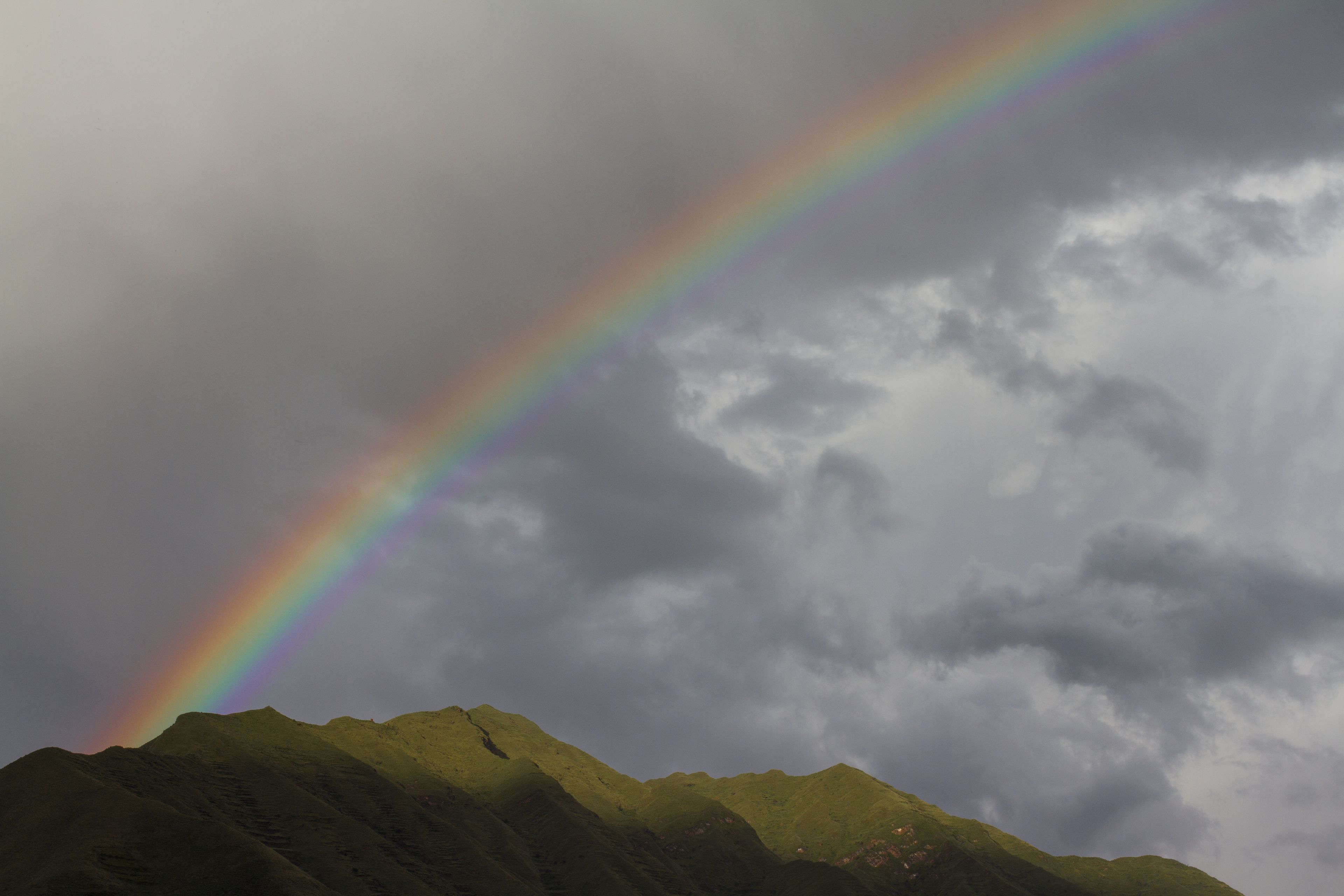 A mountain range with a rainbow arching across the sky.