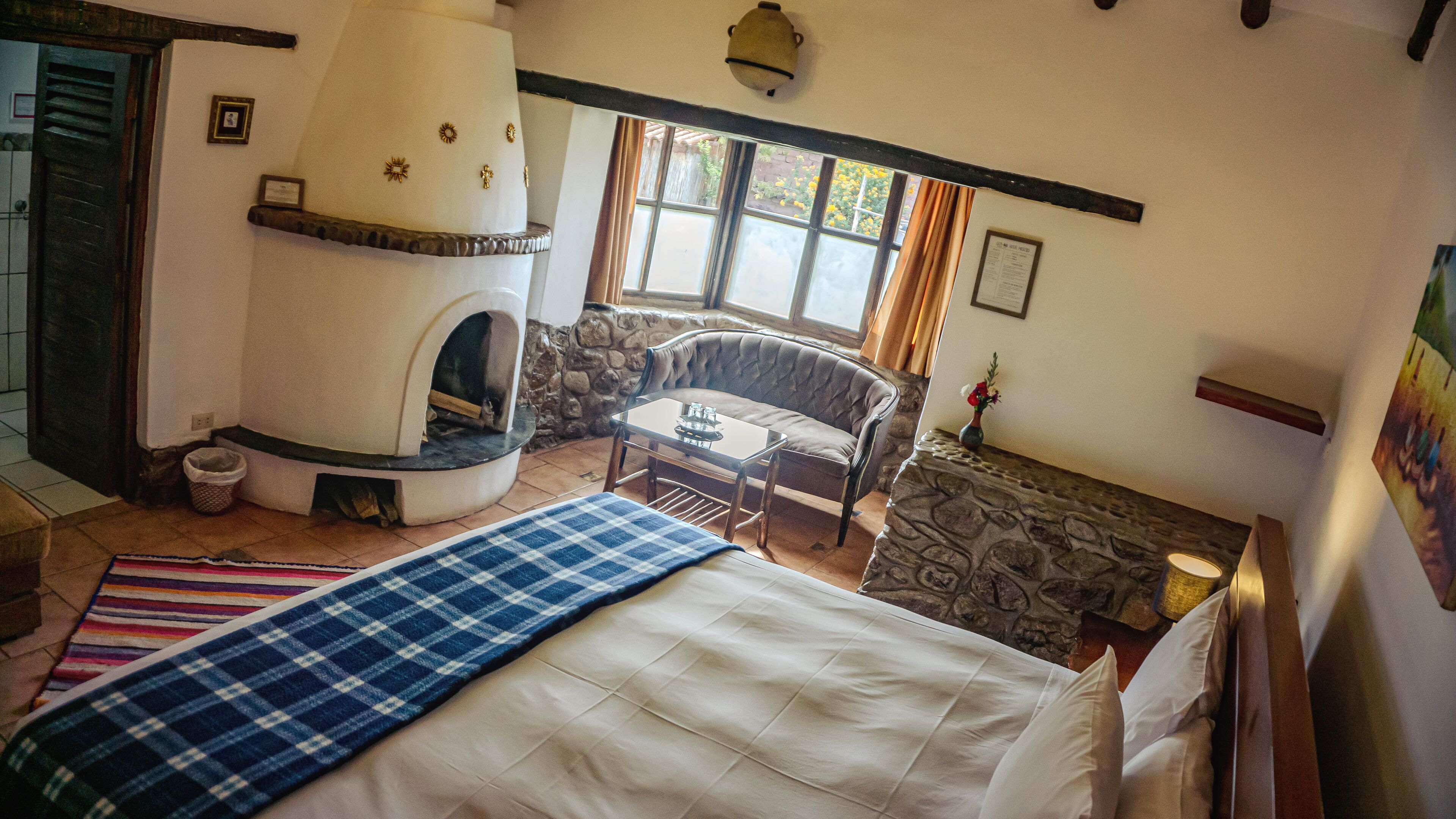 A cozy room with a fireplace, a sofa, a small table, and a bed.