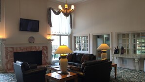 Amplia sala de estar con chimenea, sofás de cuero, una mesa de centro y un candelabro.