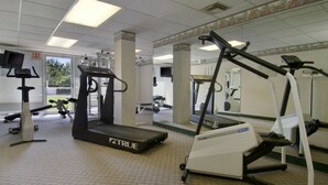 Un gimnasio con cintas de correr, escaladora y bicicleta estática.