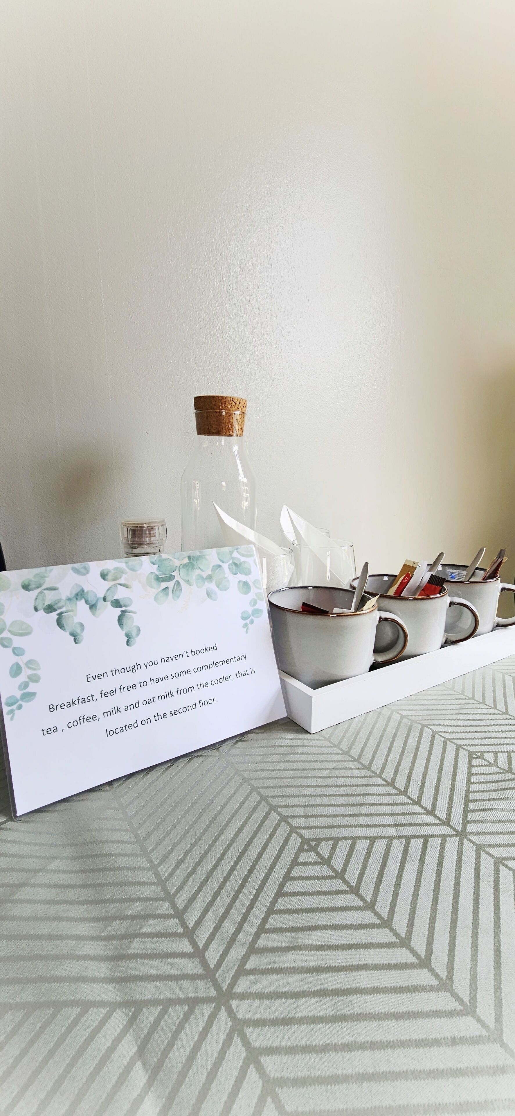 A breakfast setup with mugs, a bottle, and a card on a tray.