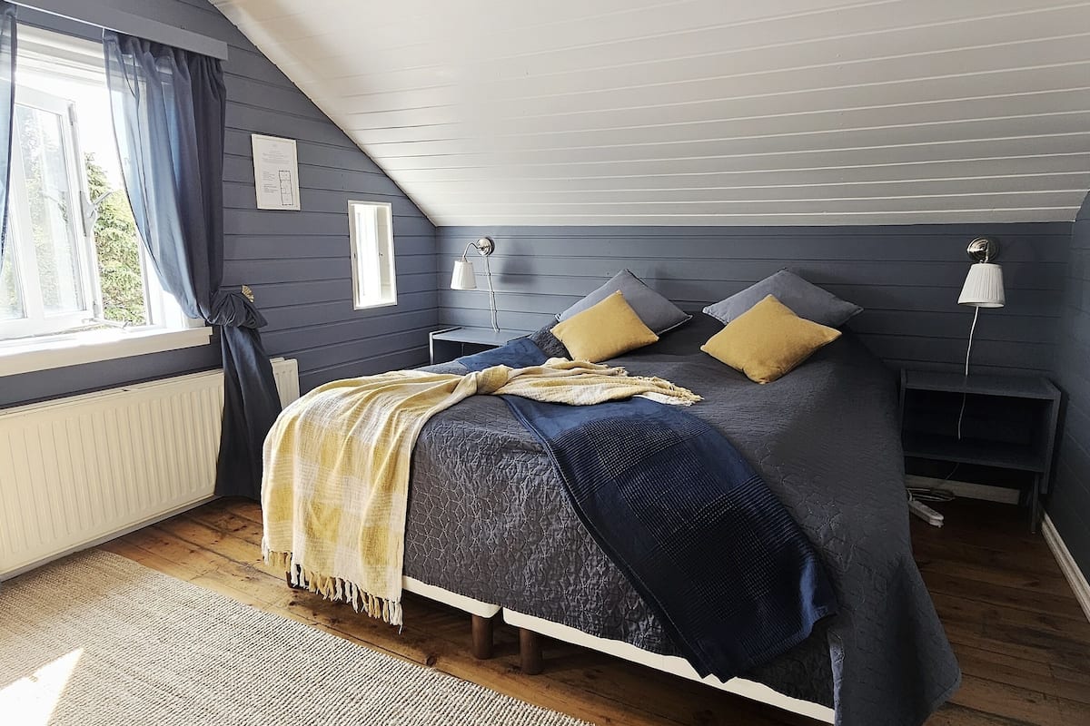 A bedroom with a bed, bedside tables, a lamp, and a window with curtains.
