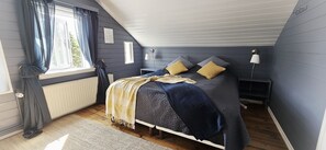 Een slaapkamer met een bed, nachtkastjes, een lamp en een raam met gordijnen.