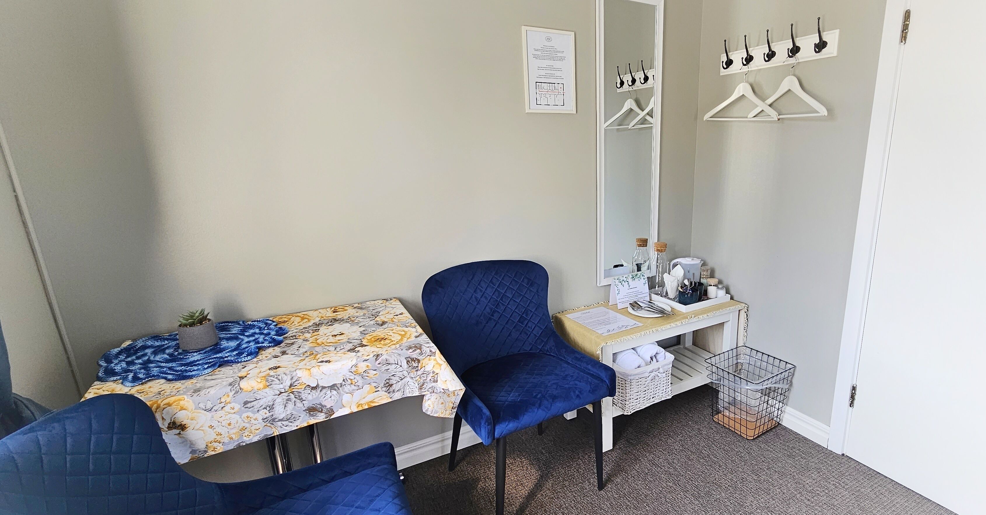 A small room with a desk, a chair, a mirror, and a hanging coat rack.