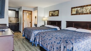 Habitación de hotel con dos camas, un aparador de madera, baño con ducha y zona de cocina.