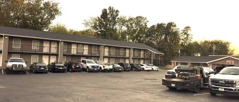 A parking lot with multiple vehicles, including cars and trucks, in front of a motel with a two-story structure and balconies.