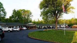 A motel with multiple rooms, a parking lot, and a flagpole with an American flag. - Kentucky Lake Inn (Gilbertsville)
