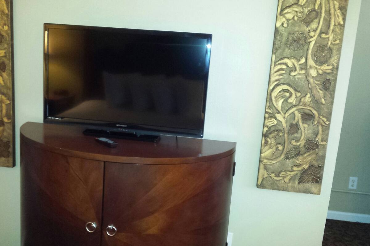 A flat-screen TV on a wooden cabinet with two decorative panels on either side.