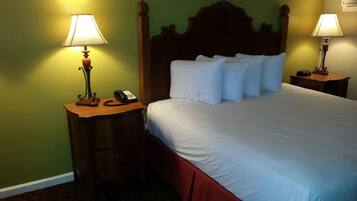A hotel room with a large bed, two bedside tables with lamps, a telephone, and a wooden headboard.
