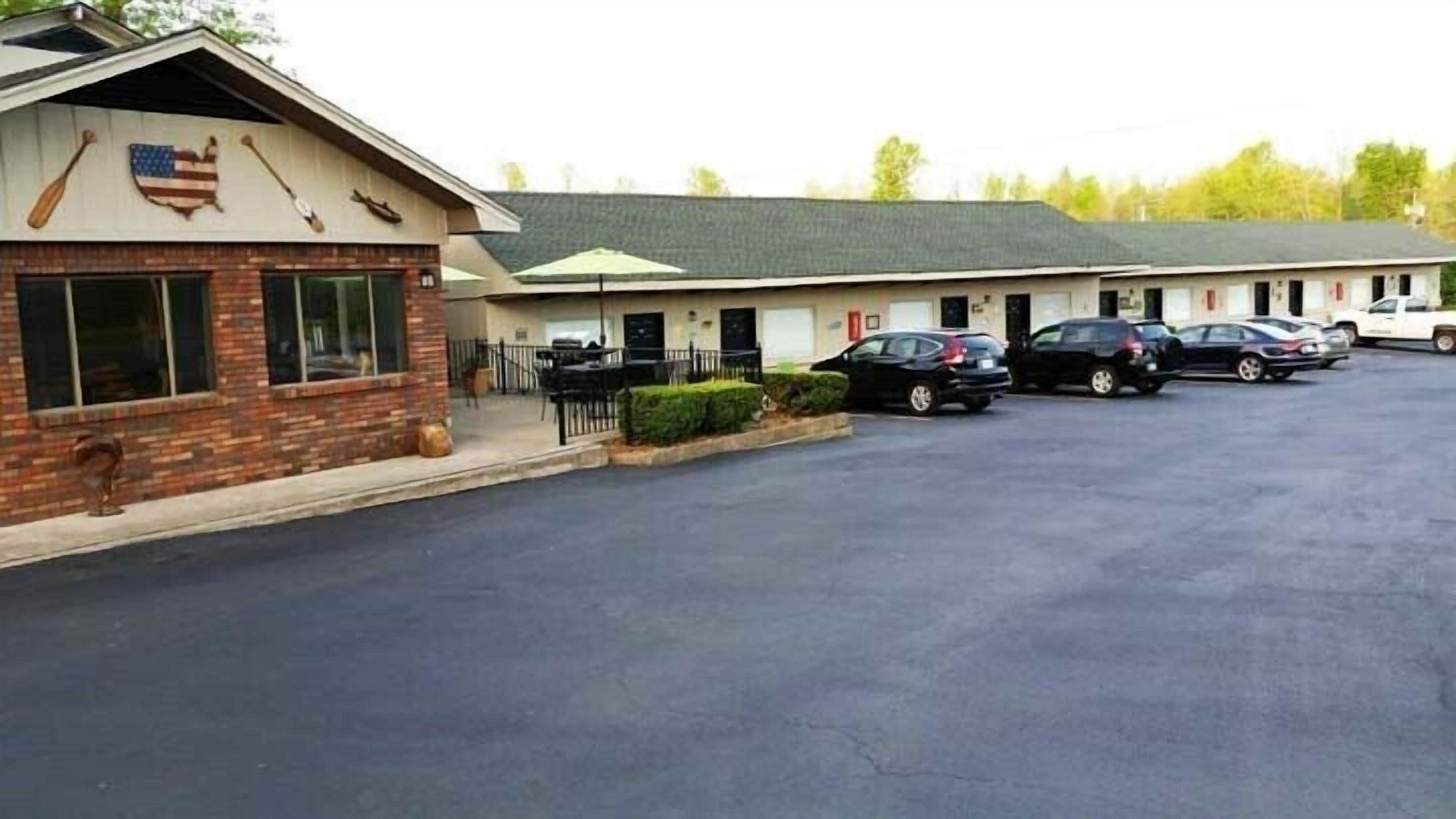 Un motel con fachada de ladrillo, un estacionamiento y varios coches aparcados al frente.