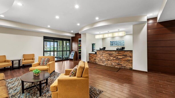 A lobby with sofas, a coffee table, a reception desk, and a stone wall.