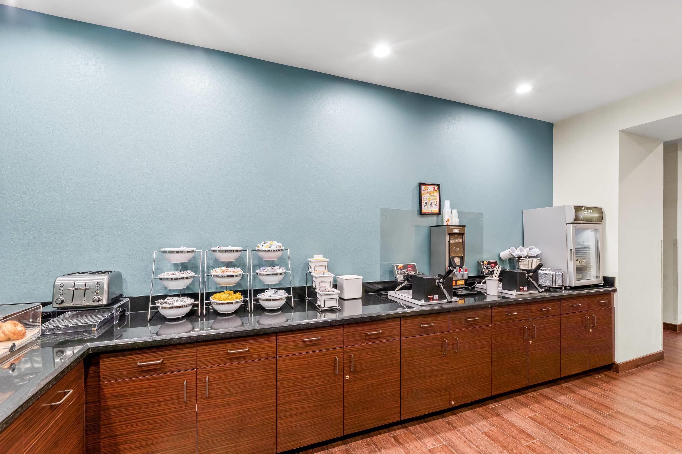 Una barra de desayuno con diversos alimentos y una máquina de café.
