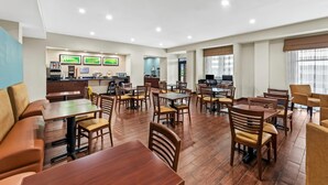 Un comedor amplio con varias mesas y sillas de madera, una barra con estación de bebidas, y una cocina al fondo.
