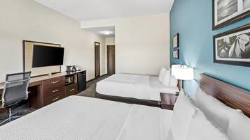 Habitación de hotel con dos camas, un escritorio con una silla, un televisor de pantalla plana y un minibar.