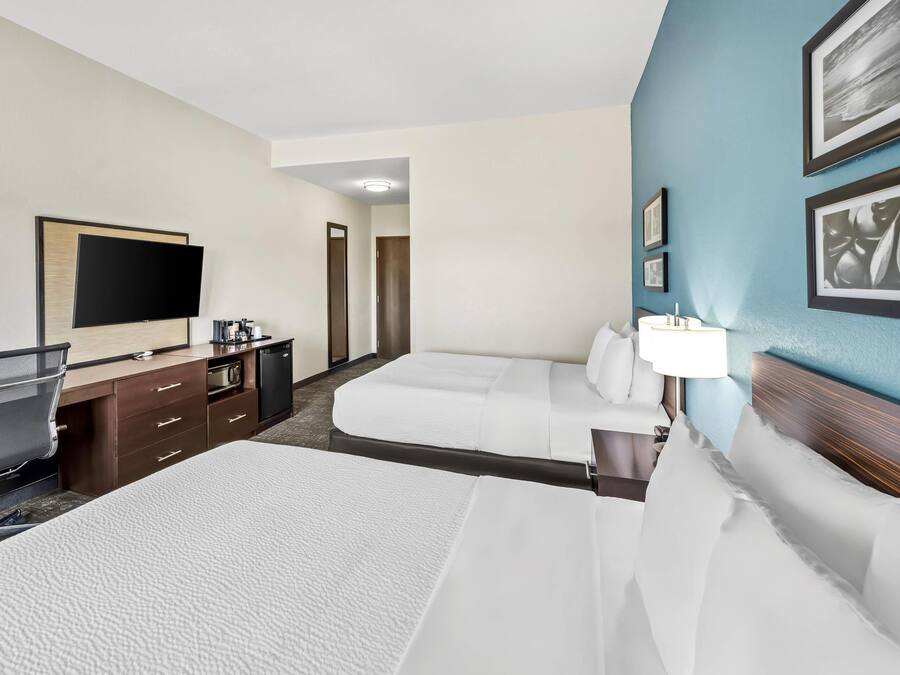 Habitación de hotel con dos camas, un escritorio con una silla, un televisor de pantalla plana y un minibar.