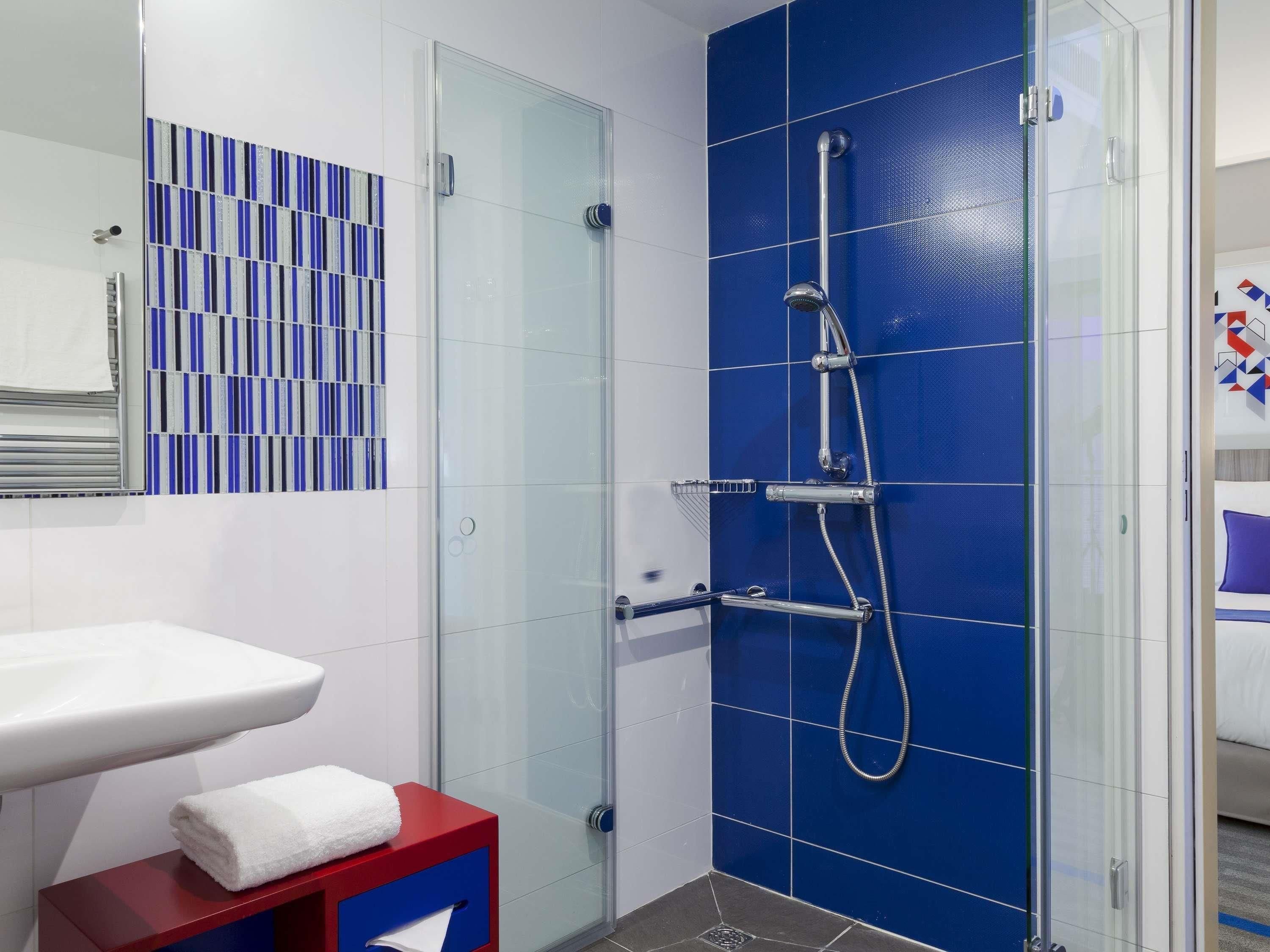 A modern bathroom with a glass-enclosed shower, a white sink, and a red vanity.