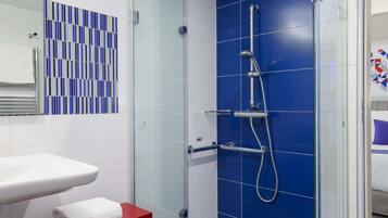 A modern bathroom with a glass-enclosed shower, a white sink, and a red vanity.