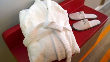 Una toalla blanca y zapatillas sobre un banco rojo.