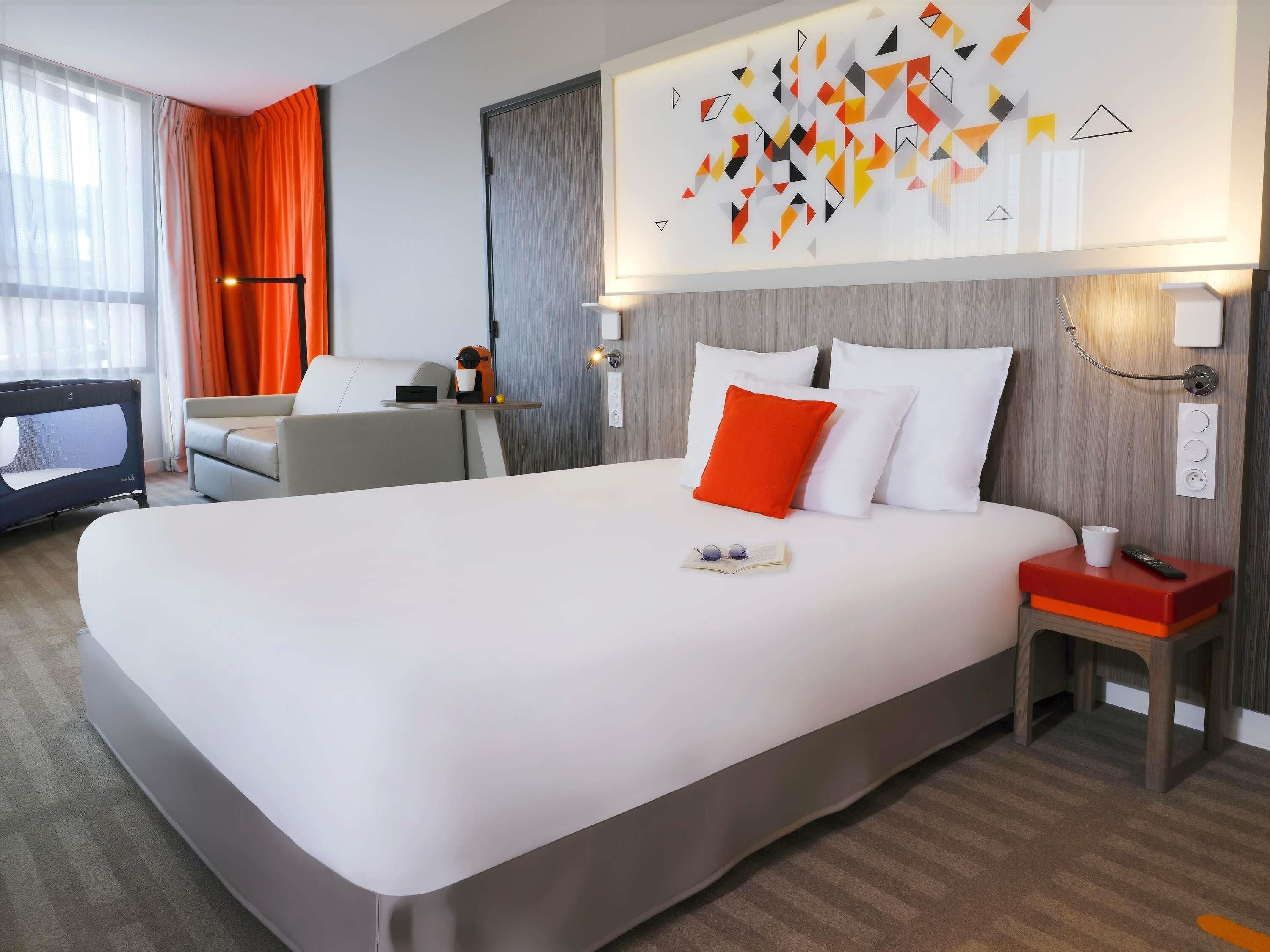 Une chambre d’hôtel moderne avec un grand lit, un bureau et une télévision.