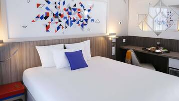 A modern hotel room with a large bed, a desk, and a wall-mounted abstract art piece.