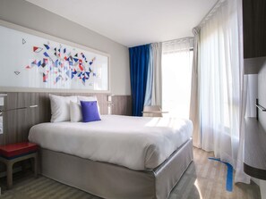 A hotel room with a large bed, a small table, a chair, and a wall art piece. - Hôtel Mercure Toulouse Sud (Toulouse)