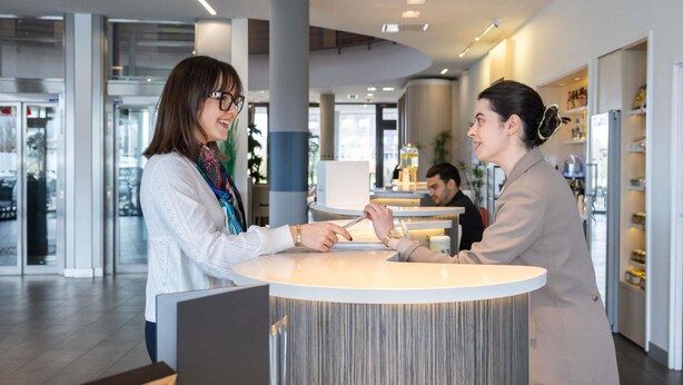 Un área de recepción con mostrador circular, entrada por puerta de vidrio y diseño interior moderno.