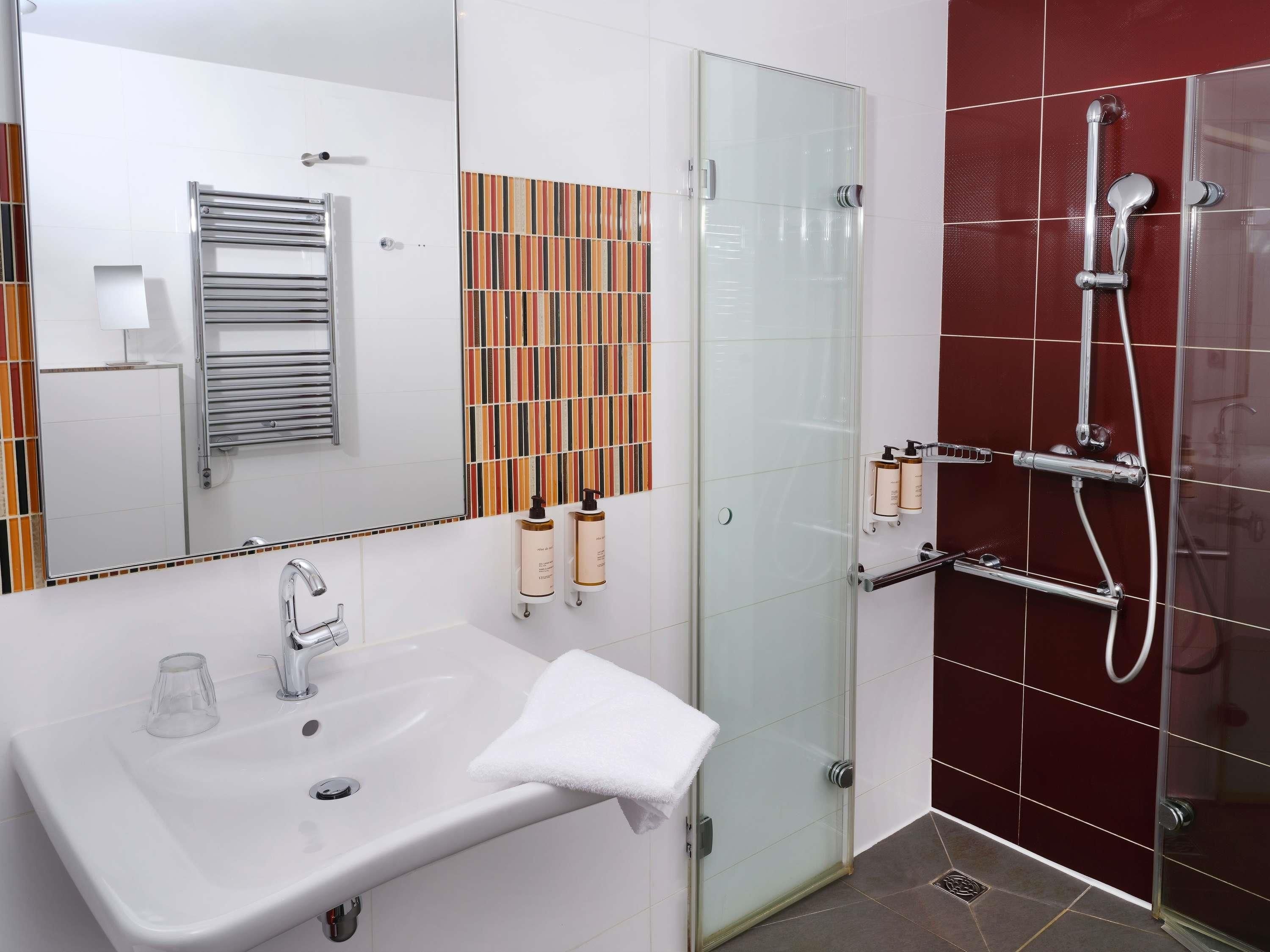 A bathroom with a white sink, a glass shower enclosure, and a towel rack.
