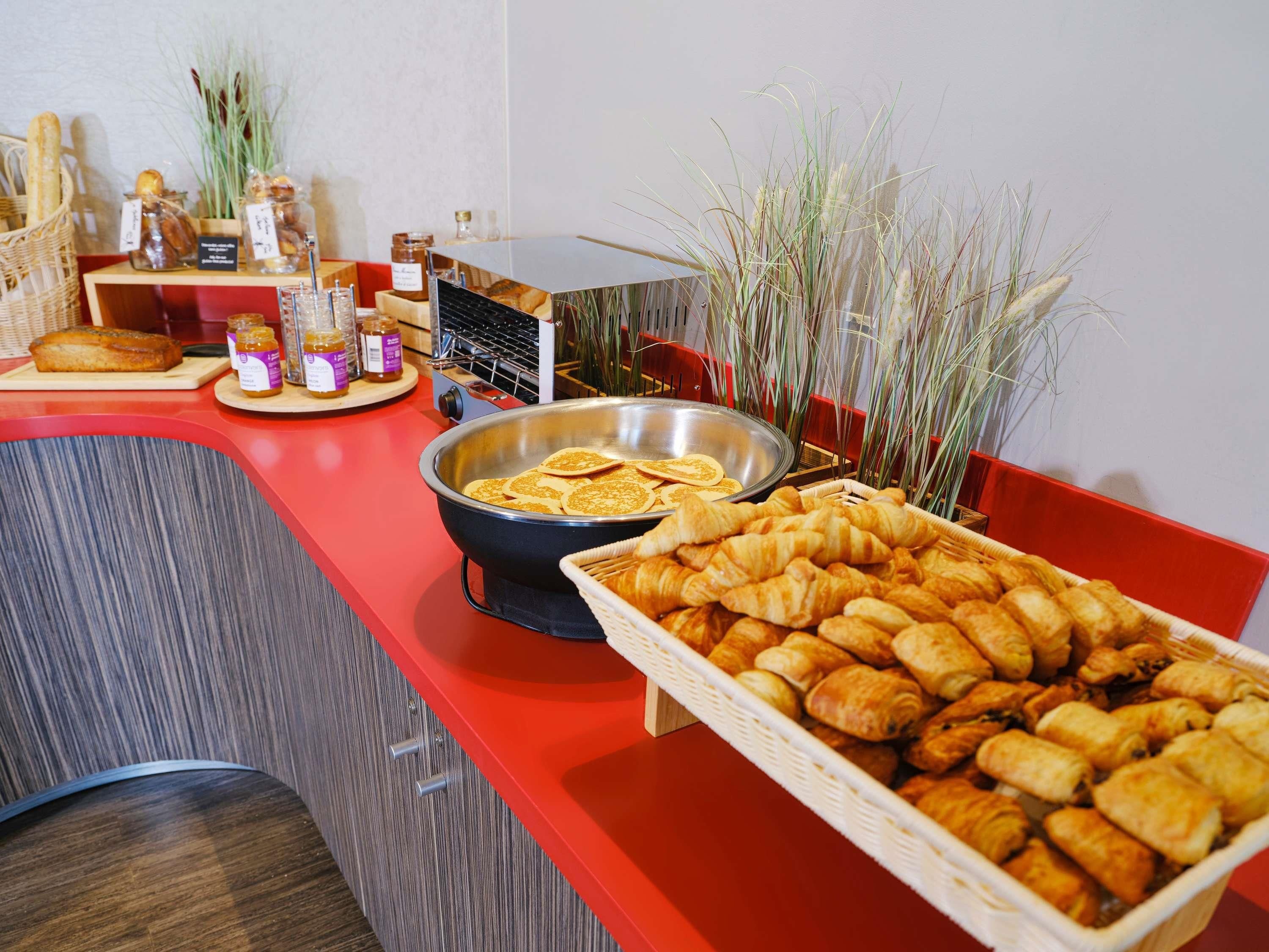Un buffet proposant une variété de produits de boulangerie, notamment du pain et des viennoiseries, ainsi qu’un grand saladier en métal.
