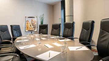 A conference room with a round table, black leather chairs, and a poster on the wall.