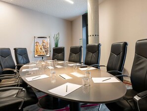 Una sala de conferencias con una mesa redonda, sillas de cuero negro y un cartel en la pared.