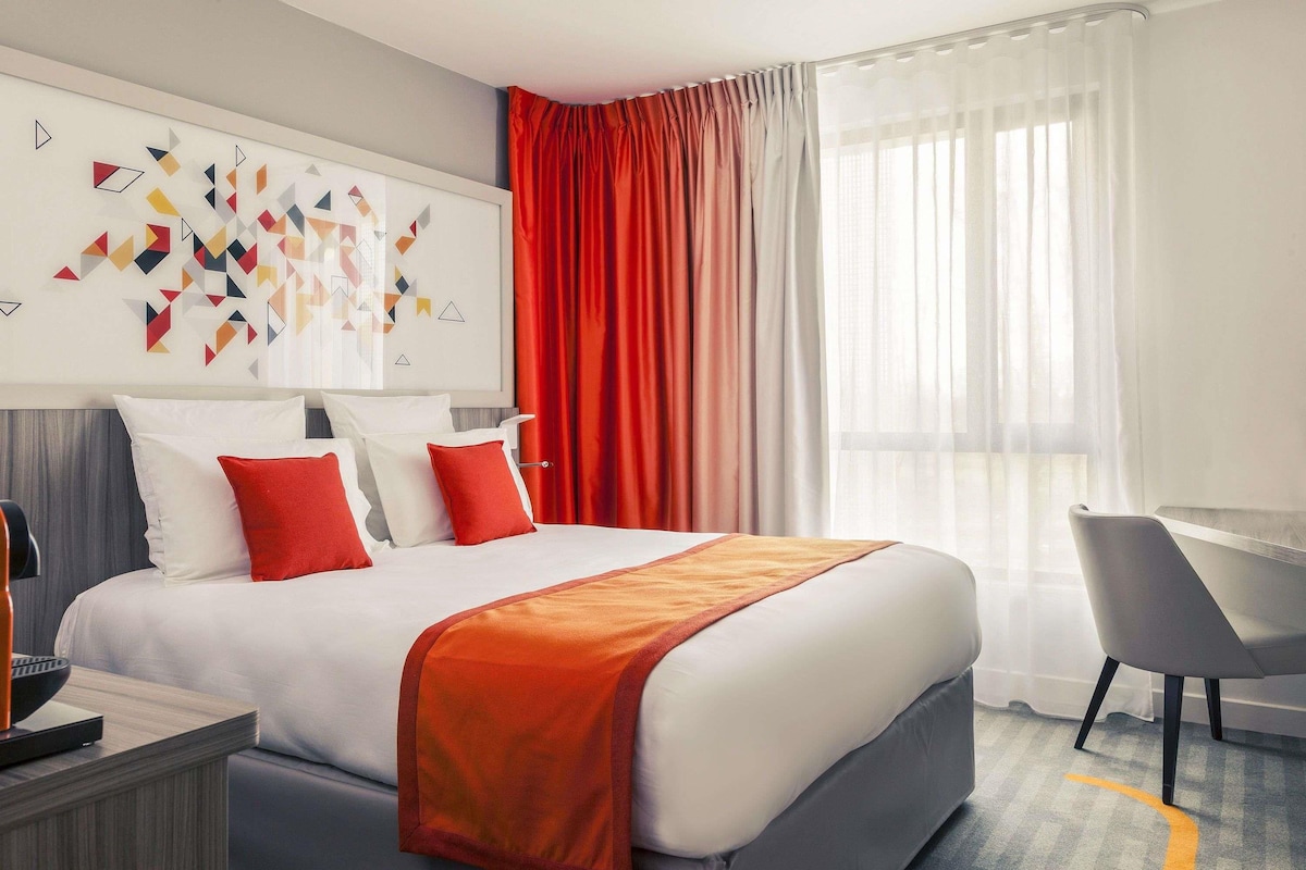Una habitación de hotel moderna con una cama grande, un escritorio y una silla.